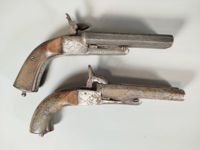 two silver pistols with wooden grips on a white surface