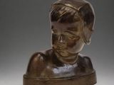 bronze bust of a young boy with a hat on his head