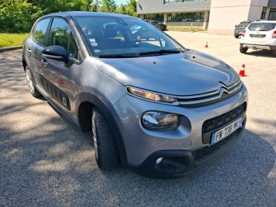 La petite voiture est garée sur le parking, à côté d'autres voitures.