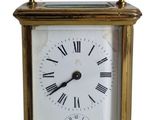 une petite horloge en laiton avec des chiffres romains sur le cadran