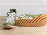 pair of green and white running shoes sitting on top of a wooden table