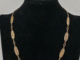 a gold necklace on a mannequin neck with a black background