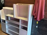 a umbrella and a shelf in a room with a painting on the wall behind it