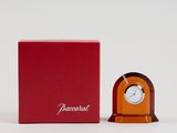 une horloge orange posée à côté d'une boîte rouge sur une surface blanche