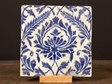 un carreau bleu et blanc posé sur un socle en bois