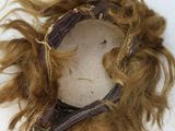 a brown wig on a white surface with hair blowing in the wind