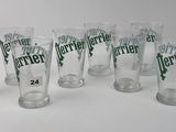 six verres transparents portant des inscriptions vertes sont alignés sur une surface blanche