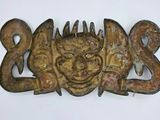 a wooden carving of a face with horns on it