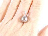 a woman ' s hand holding a ring with a black pearl on it