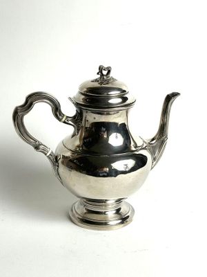a silver tea pot sitting on a white surface