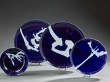 quatre assiettes bleues ornées de motifs blancs, posées sur une table