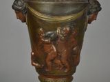 a bronze vase on a stand on a gray background