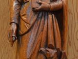une statue en bois représentant un homme avec un chat posé sur une table