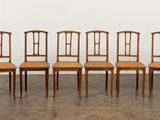 six chaises sont alignées en rangée contre un mur blanc
