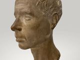 a close up of a statue of a man ' s head on a wooden stand