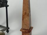 a small stone obelisk next to a small metal vase