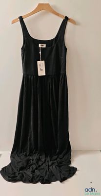 La robe noire est suspendue à un cintre accroché au mur.