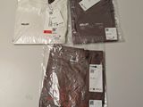 trois t-shirts et un pantalon sont posés sur une table