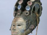 une image représentant un masque en bois posé sur un socle en métal