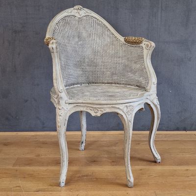 une chaise blanche avec une assise en osier posée sur un sol en bois
