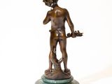 bronze statue of a boy holding a bird on a marble base