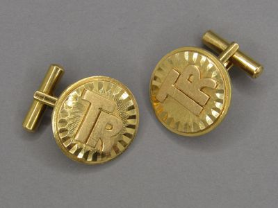 une paire de boutons de manchette en or sur lesquels figure la lettre « t »