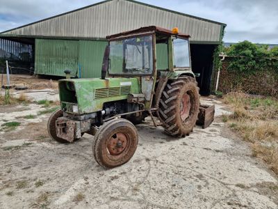 a green tractor that is parked in front of a building