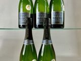 quatre bouteilles de champagne sont posées sur une étagère en verre