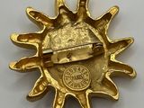 an image of a gold broochle with a sun on it