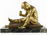 bronze statue of a man sitting on a marble base holding a cup