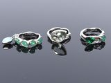 three silver rings with green stones on a black surface