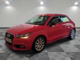 L'Audi rouge est garée dans une grande pièce au sol carrelé.