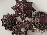 a picture of a brooch with red stones on it
