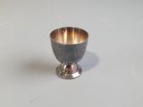 a silver cup sitting on a table with a white background