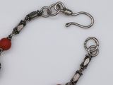 bracelet with red beads and silver clasps on a white surface