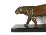 statue d'un tigre posée sur un socle noir, devant un mur blanc