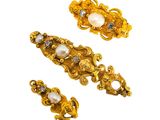 a close up of a pair of gold and pearl brooches