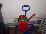 une petite voiture jouet rouge et bleue sur laquelle sont posés des outils