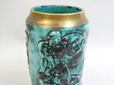 un vase bleu bordé d'or posé sur une surface blanche