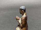 small bronze figurine of a boy sitting on his knees