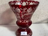 un vase en verre rouge posé sur une table, avec une étiquette dessus