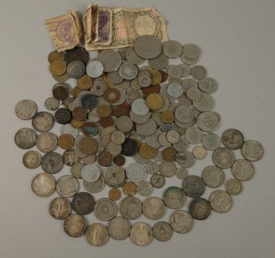 une pile de pièces de monnaie posée sur la table, à côté d'une liasse de billets