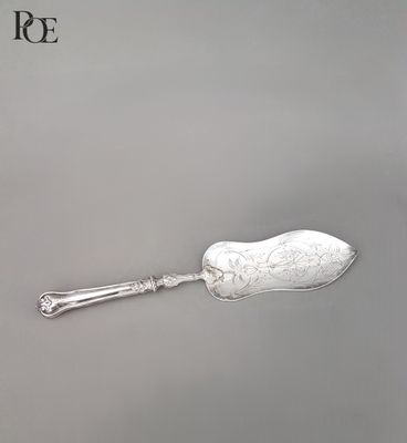 une cuillère ancienne en argent à long manche posée sur une surface grise