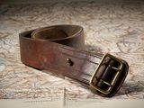 une ceinture marron avec une boucle en laiton posée sur une carte