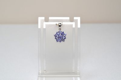 a close up of a necklace with a blue flower on it