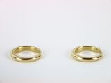 two gold wedding rings sitting on top of a white surface