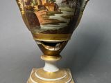 a vase with a painting on it sitting on a stand
