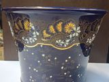 un vase bleu orné de motifs dorés, posé sur une table