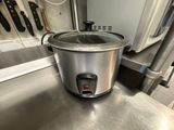 une mijoteuse argentée posée sur un plan de travail en inox