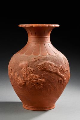 un vase orange orné d'un dragon, posé sur une table